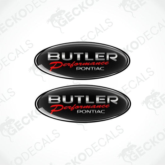 Two black oval vinyl stickers with a silver  emblem design PONTIAC BUTLER PERFORMANCE , placed against a black background.