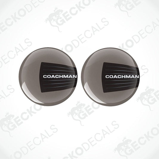 Two round black and white vinyl decals with the text 'COACHMAN' on them, placed on a transparent background.