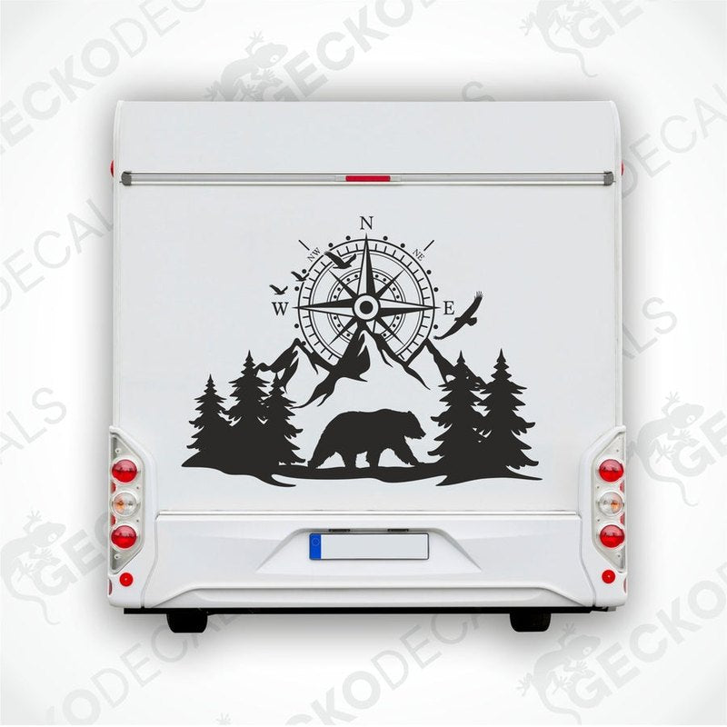 A black decal of a compass with bear and trees on the side of a white vehicle.