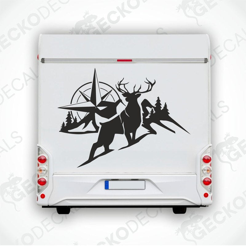 A black and white decal of a compass with mountain and forest background, and a deer in the foreground.