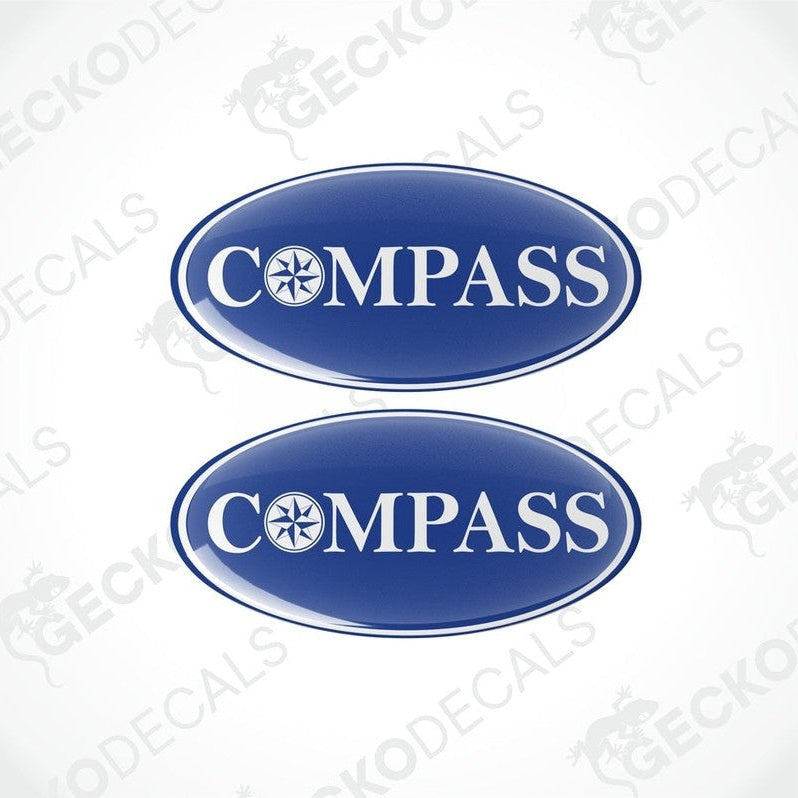 Two blue vinyl decals with the word 'COMPASS' written on them, placed against a white background.