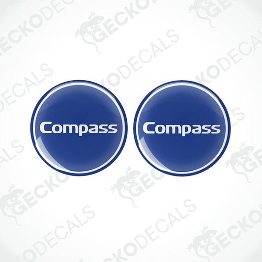 Two blue vinyl decals with the word 'Compass' printed on them, placed against a white background.
