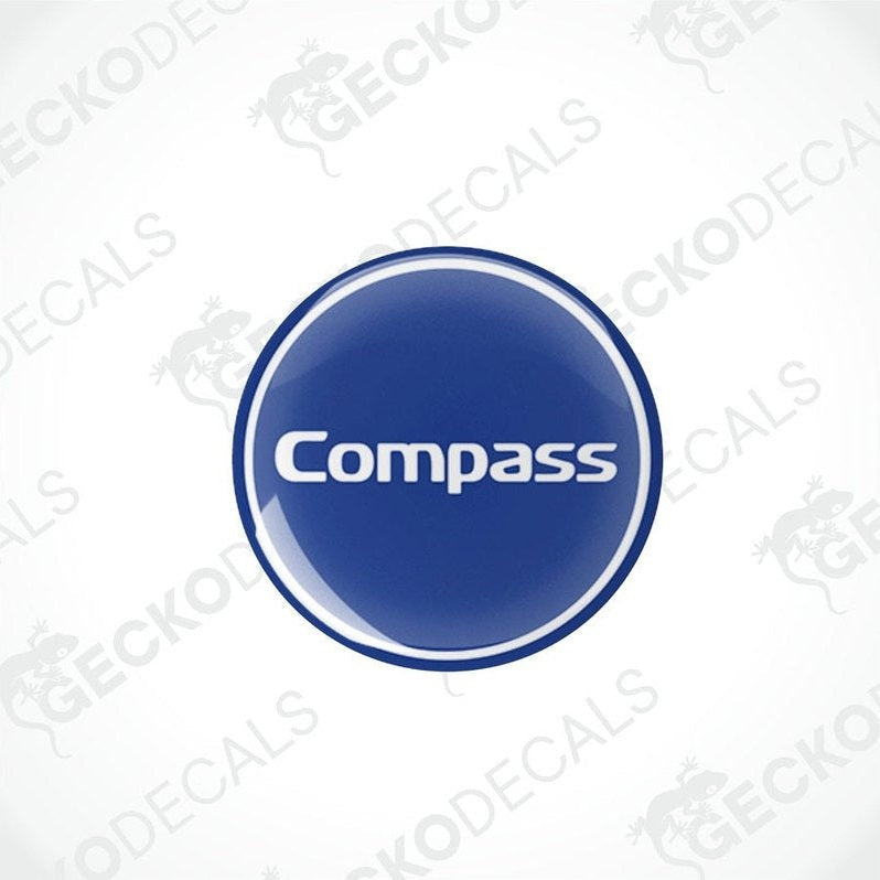 Two blue vinyl decals with the word 'Compass' printed on them, placed against a white background.