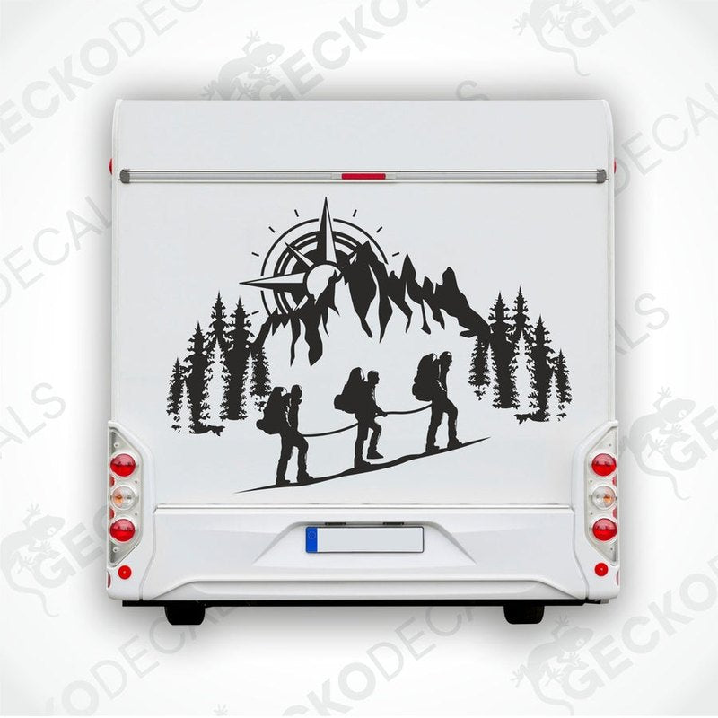 A black and white decal of a compass and people climbing a mountain.