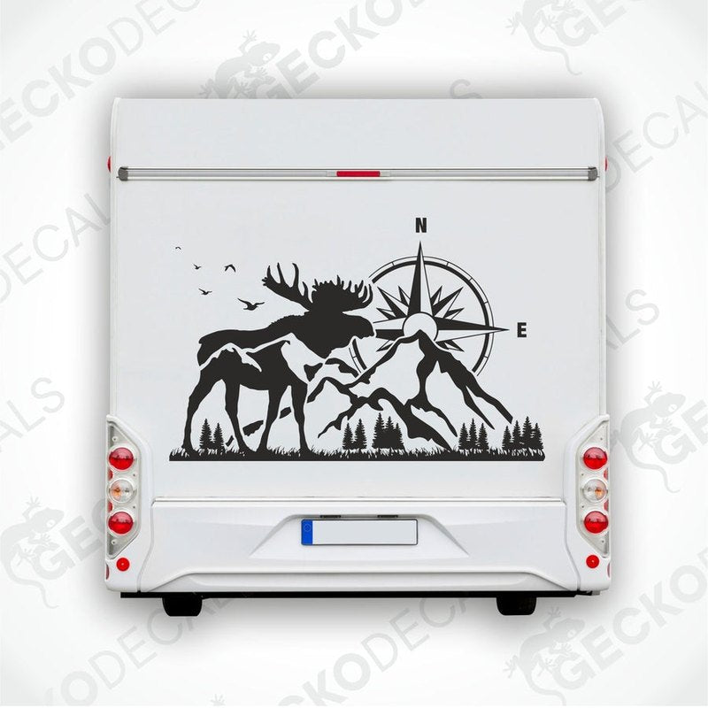 A white vehicle decal featuring a black moose with a compass in the center, surrounded by a forest and mountain landscape.