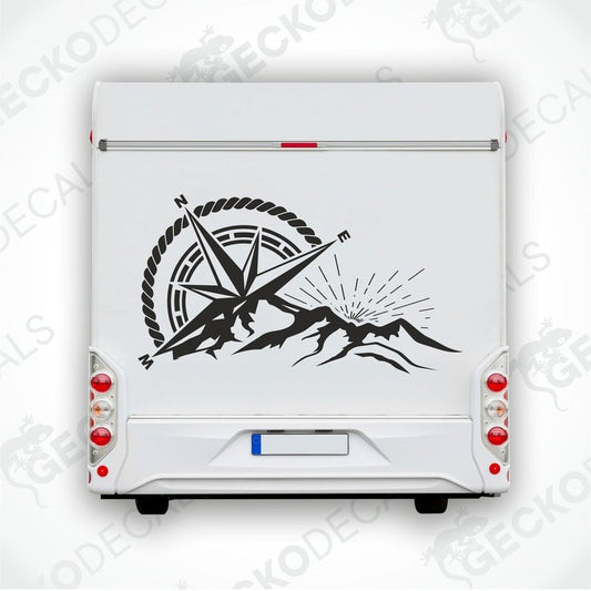 A black and white die cut decal of a compass with mountains and a sun in the center, displayed on a white vehicle.