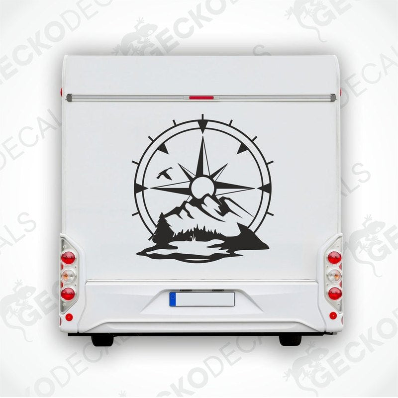 A white vehicle decal with a compass design, mountains, and a sun motif.