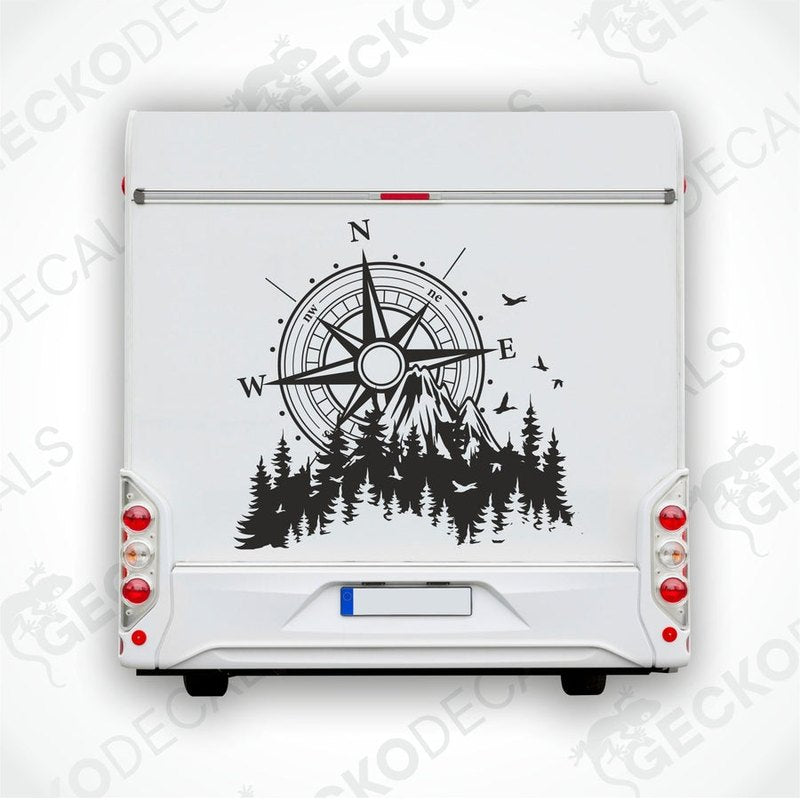 A black and white decal of a compass with mountains and trees on a vehicle.