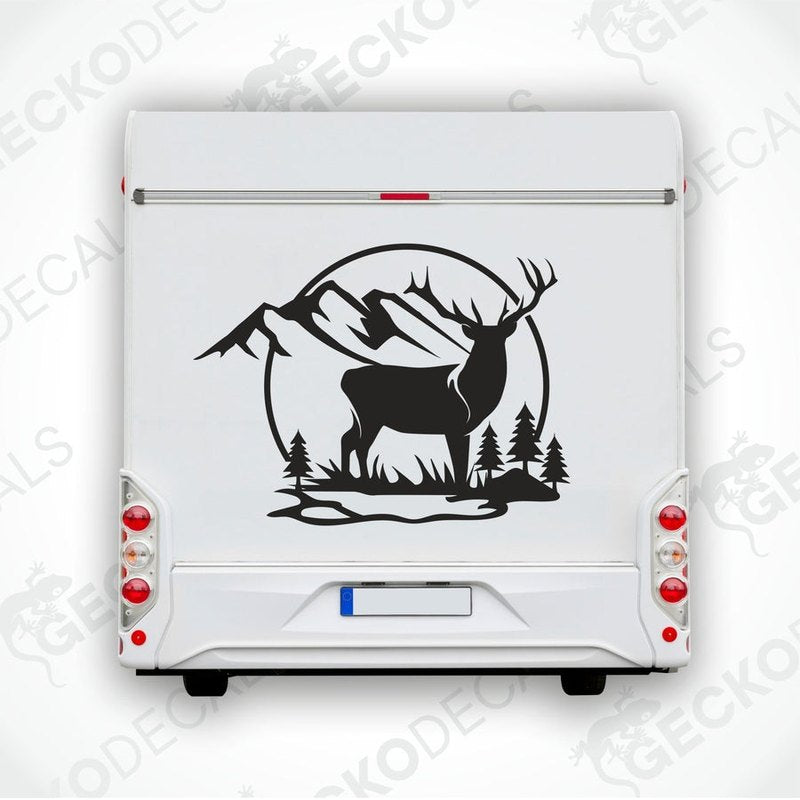 A die cut decal of a deer in a mountainous nature setting, applied on the rear of a white vehicle.