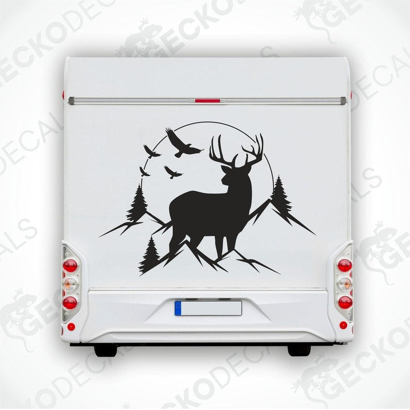 A decal featuring a silhouette of a deer in a mountainous landscape with trees and a sunset.