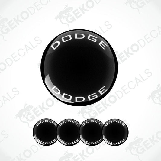 A set of black vinyl decals with the word 'DODGE' written in white letters, designed for use as car wheel caps or stickers.