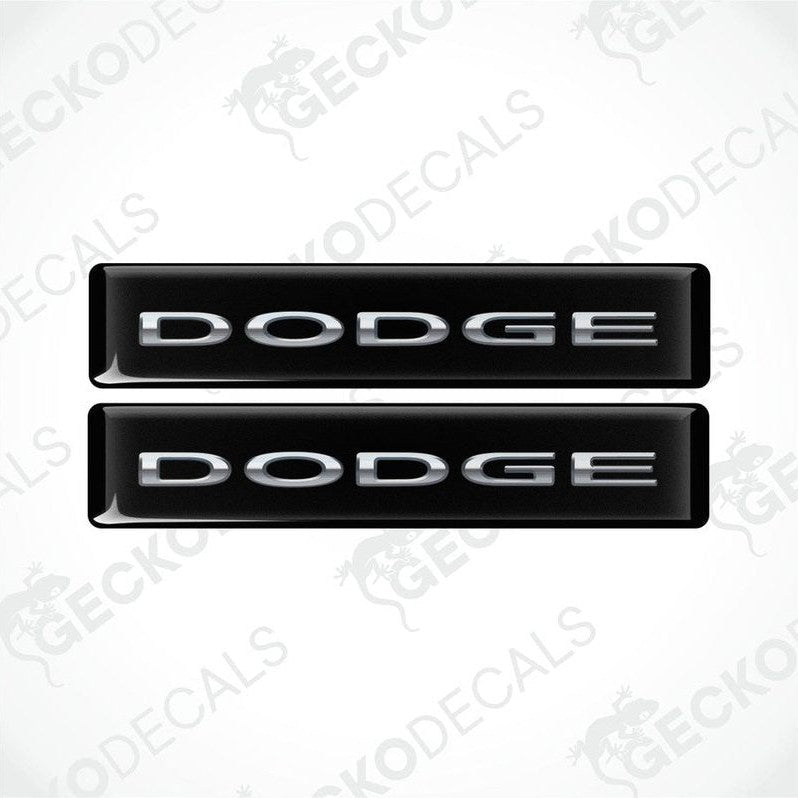 Two black vinyl decals with the word 'DODGE' written in silver letters.