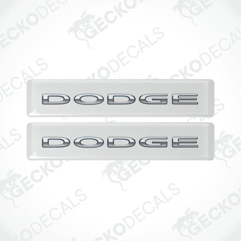 Two white vinyl decals with the word 'DODGE' written in silver letters.
