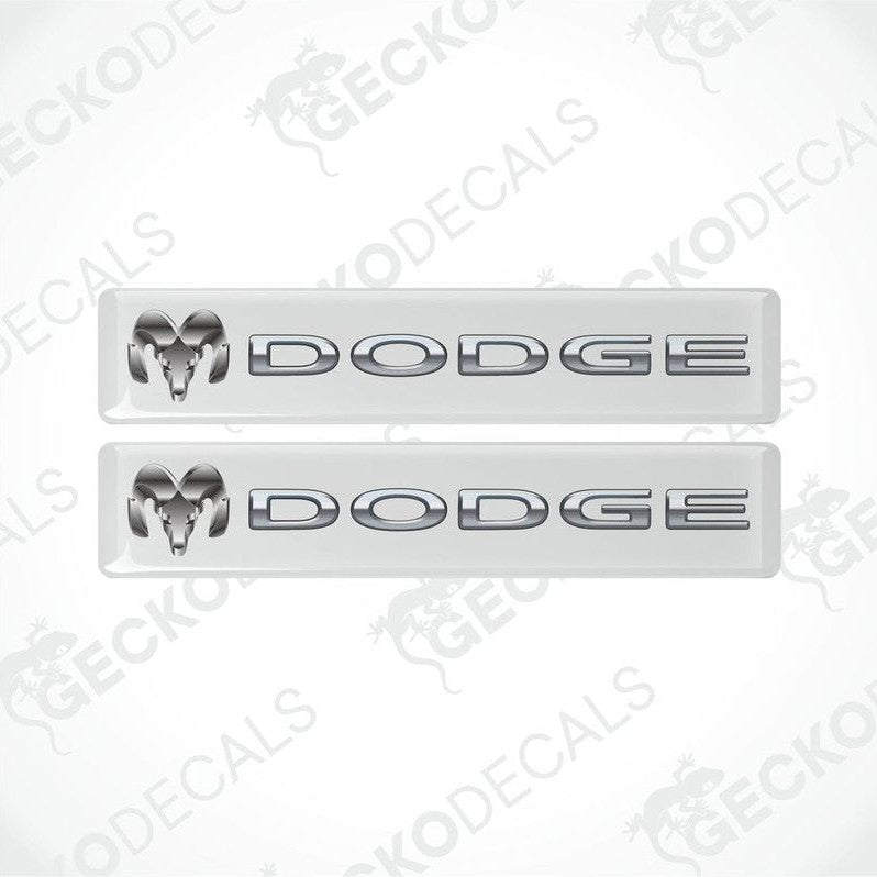 Two white vinyl stickers with the word 'Dodge' printed on them.