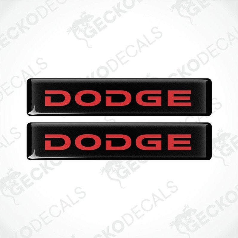 Two black and black vinyl stickers with the word "DODGE" printed in red.