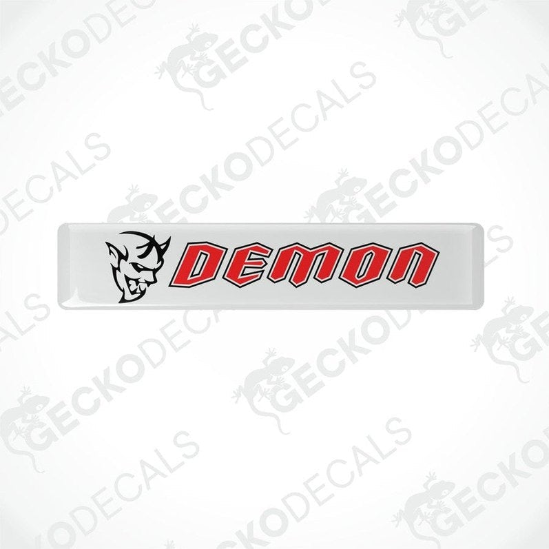  White vinyl stickers with the word 'DEMON' written in red. One sticker has a graphic of a demon above the text, and both are branded with 'GECKODECALS'.