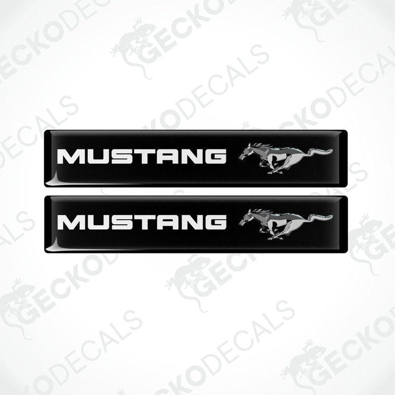 Two black vinyl stickers with the word 'MUSTANG' and an image of a horse and rider on them, placed against a white background.