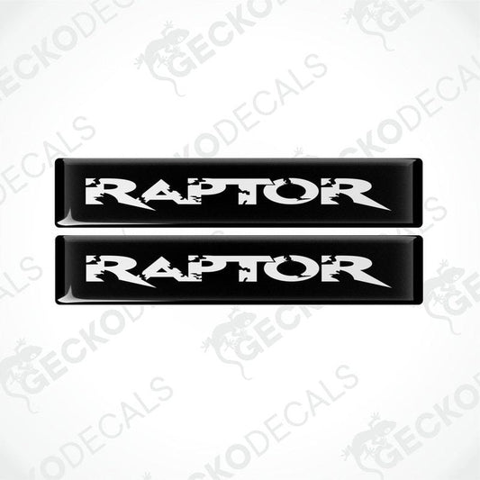 Two black and white rectangular car decals with the word 'RAPTOR' written on them in bold lettering.