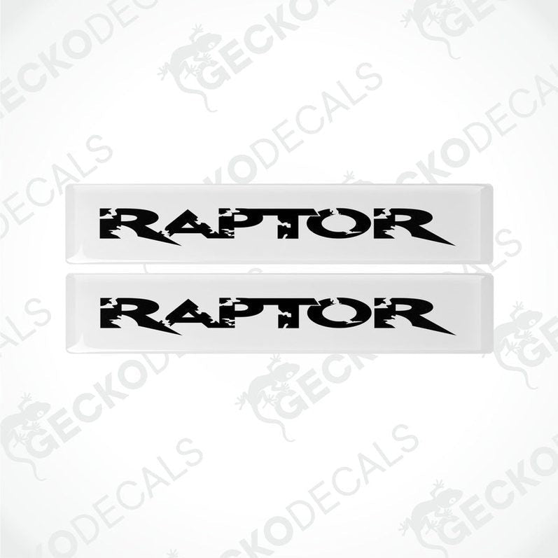 Two white and black rectangular car decals with the word 'RAPTOR' written on them in bold lettering.