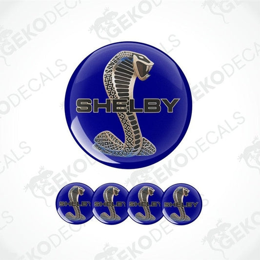 A three-dimensional light red Shelby cobra logo with a gold frame on a blue background, with the SHELBY lettering in the center
