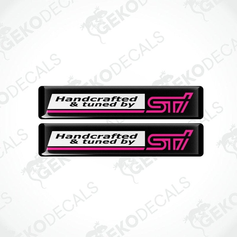 Two black vinyl stickers with 'HANDCRAFTED & TUNED BY STI' text, featuring a pink and withe color scheme.