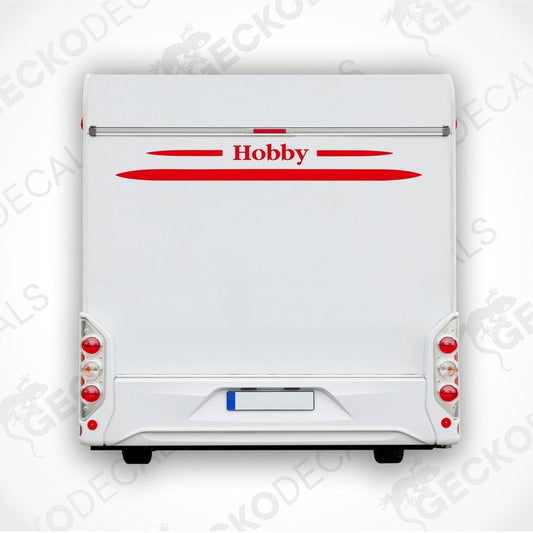 A white caravan with a red horizontal decal on the rear side, featuring the brand name 'Hobby' in bold lettering.