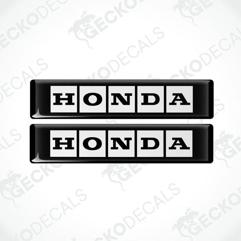Two rectangular black and white vinyl decals with the text 'HONDA' displayed on them.