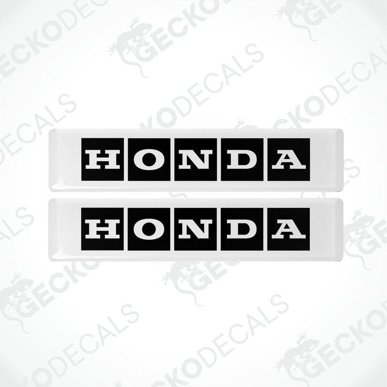Two rectangular white and black vinyl decals with the text 'HONDA' displayed on them.