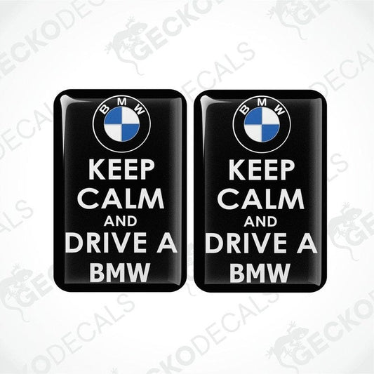 Two rectangular black vinyl decals with the text 'KEEP CALM AND DRIVE A BMW' in white, and the BMW logo in blue and white.