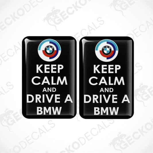 Two black vinyl stickers with the text 'KEEP CALM AND DRIVE A BMW' and the BMW logo.