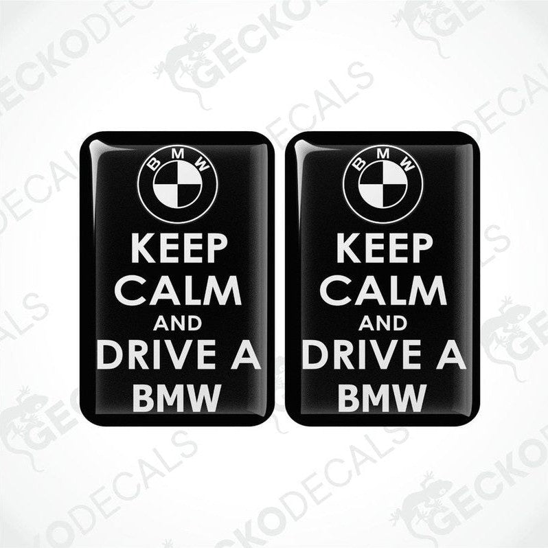 Two rectangular black vinyl decals with the text 'KEEP CALM AND DRIVE A BMW' in white, and the BMW logo above the text.