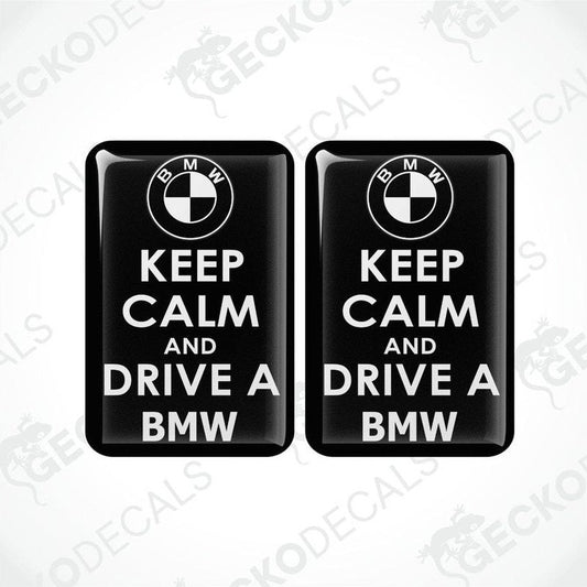 Two rectangular black vinyl decals with the text 'KEEP CALM AND DRIVE A BMW' in white, and the BMW logo above the text.
