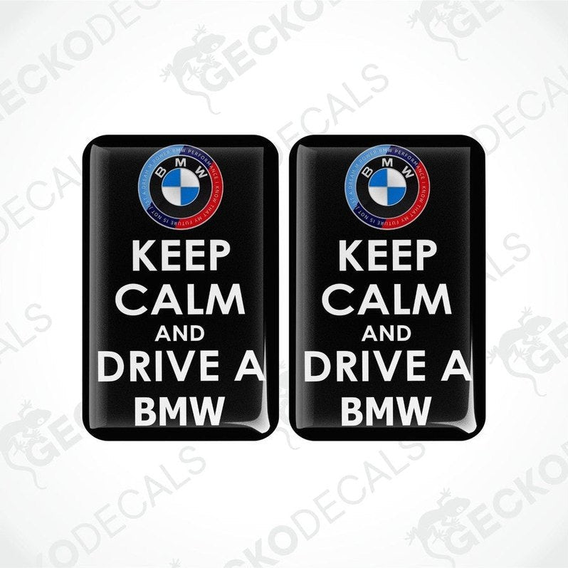 Two rectangular vinyl decals with a polyurethane coating, featuring the text 'KEEP CALM AND DRIVE A BMW' and the BMW logo.