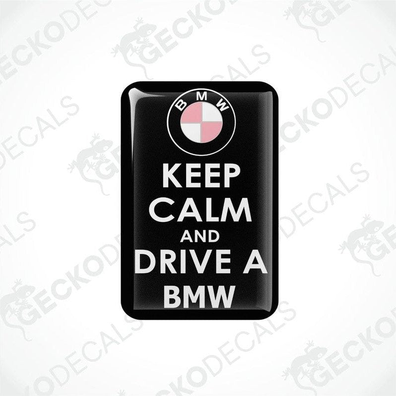 Rectangular black vinyl decals with the text 'KEEP CALM AND DRIVE A BMW' and the BMW logo in pink.