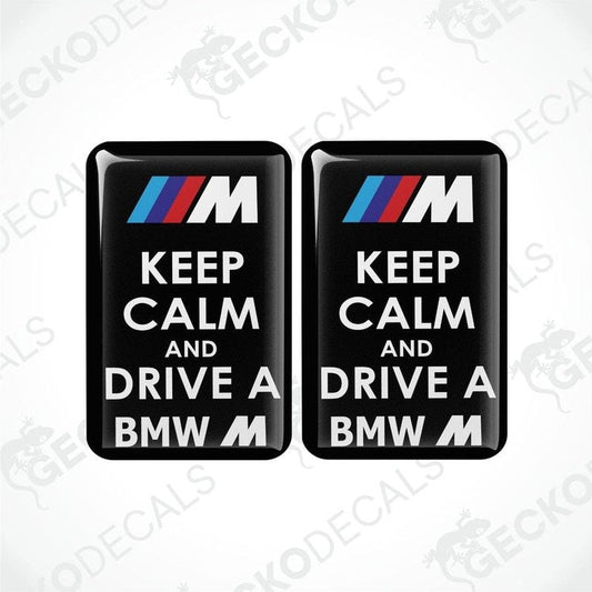 Two rectangular black vinyl decals with the text 'KEEP CALM AND DRIVE A BMW M' in white and red letters, featuring the BMW M logo.