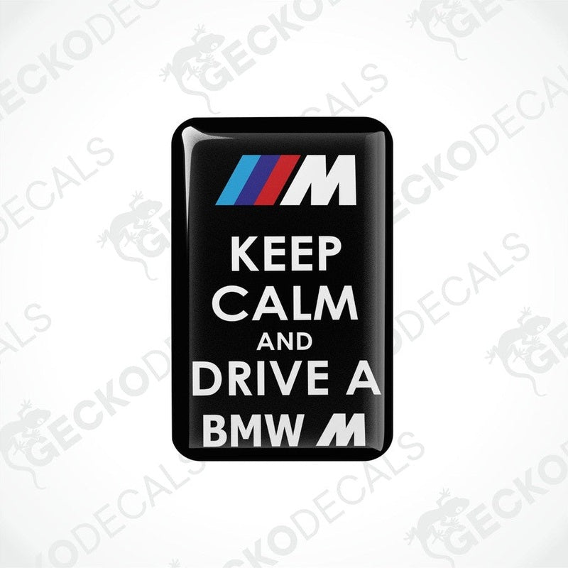 Rectangular black vinyl decals with the text 'KEEP CALM AND DRIVE A BMW M' in white and red letters, featuring the BMW M logo.