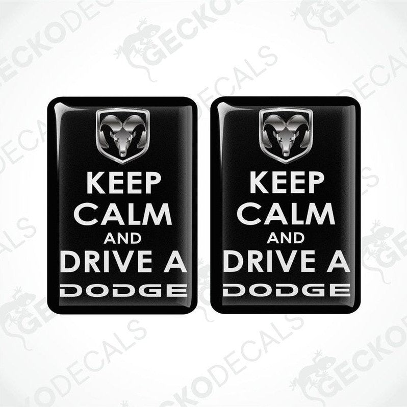 Two black vinyl decals with white text saying 'KEEP CALM AND DRIVE A DODGE' and the Dodge ram logo.