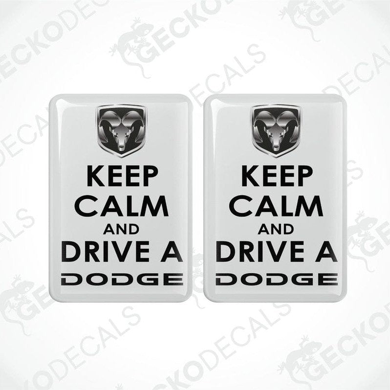 Two white vinyl decals with black text saying 'KEEP CALM AND DRIVE A DODGE' and the Dodge ram logo.