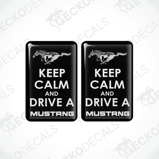 Two rectangular black vehicle decals with white text and graphics, one depicting a pony and the other the phrase 'KEEP CALM AND DRIVE A MUSTANG'.