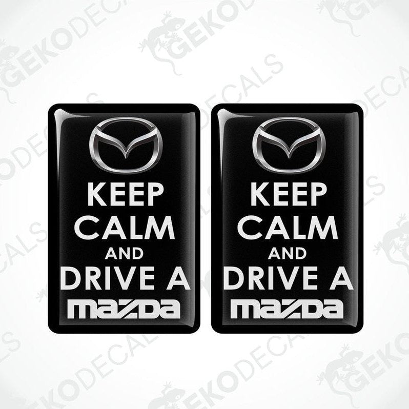 Two black vinyl stickers with the text 'KEEP CALM AND DRIVE A MAZDA' and the Mazda logo.