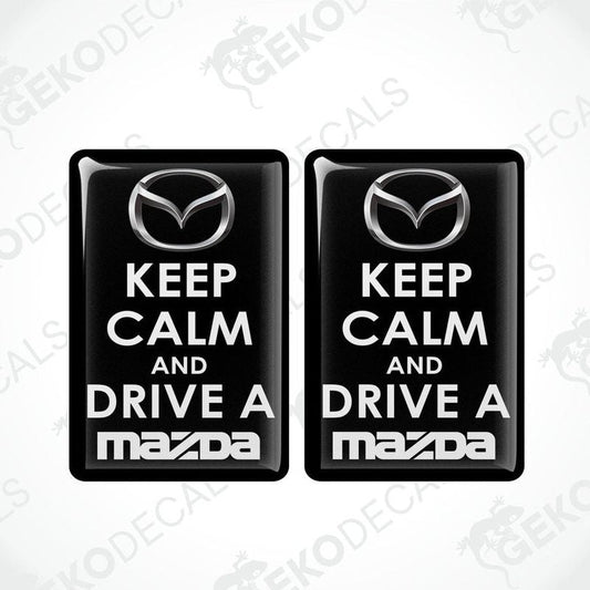 Two black vinyl stickers with the text 'KEEP CALM AND DRIVE A MAZDA' and the Mazda logo.