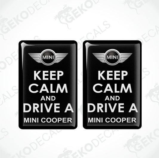 Two black vinyl stickers with the text 'KEEP CALM AND DRIVE A MINI COOPER' and the MINI COOPER logo in the center.