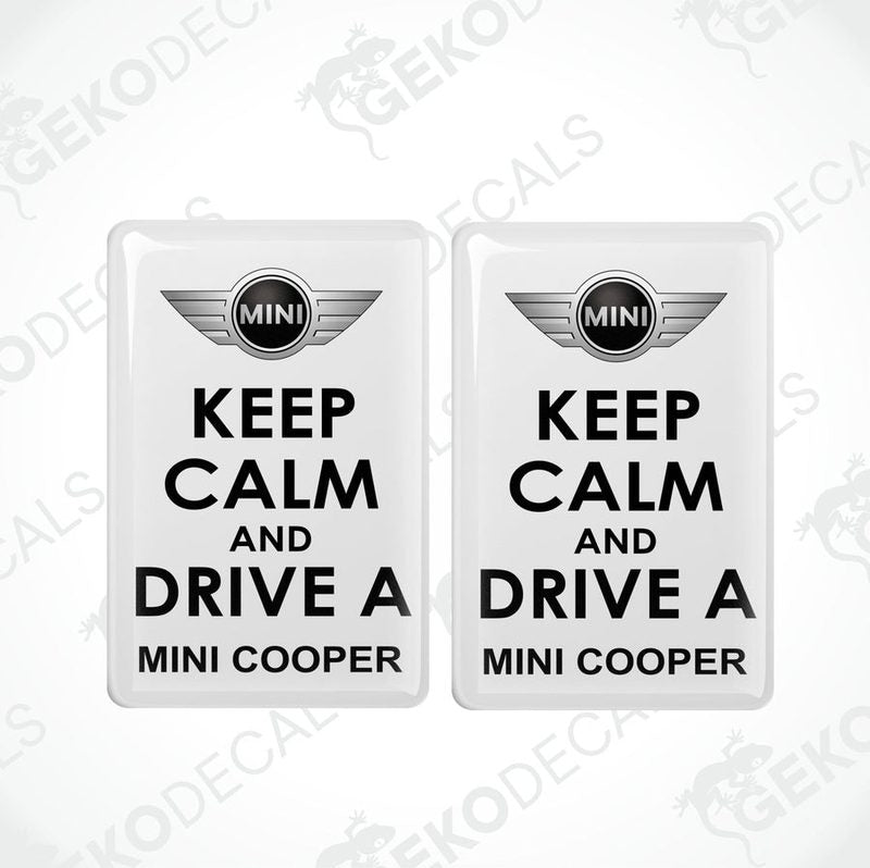 Two white vinyl stickers with the text 'KEEP CALM AND DRIVE A MINI COOPER' and the MINI COOPER logo in the center.