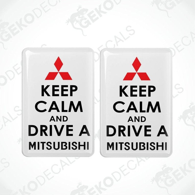Two white vinyl stickers with the text 'KEEP CALM AND DRIVE A MITSUBISHI' and a black triangle logo on each sticker.