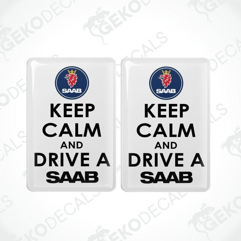 Two rectangular withe vinyl decals with black text and the Saab car logo at the top, one decal saying 'KEEP CALM AND DRIVE A SAAB' and the other with a mirror image of the text and logo.