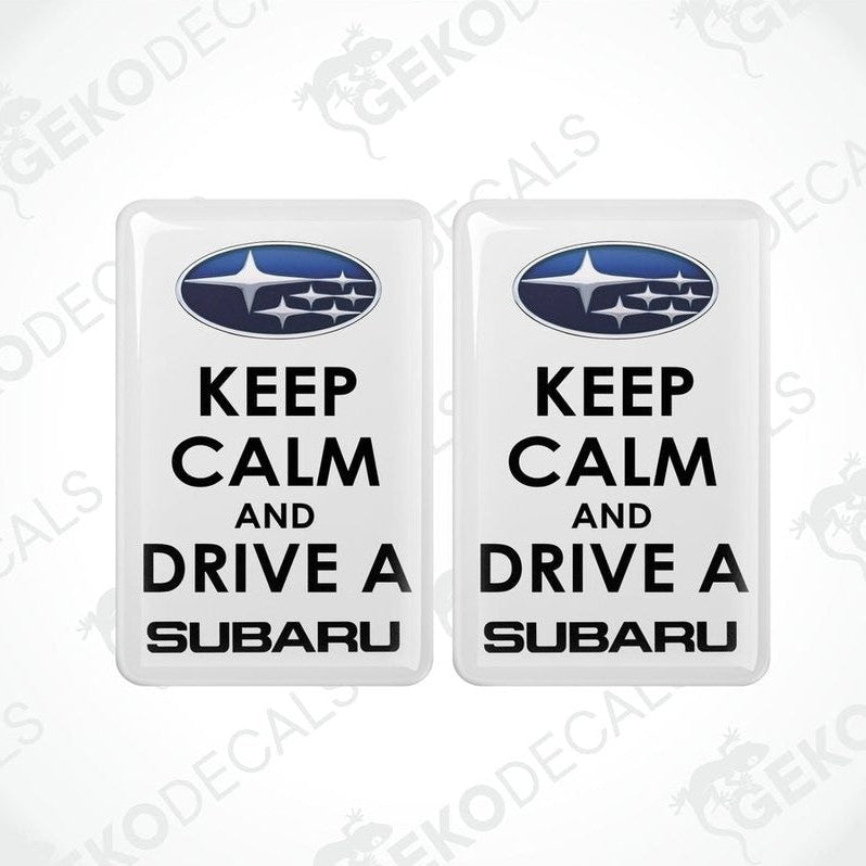 Two withe vinyl stickers with the text 'KEEP CALM AND DRIVE A SUBARU' and the Subaru logo above the text.