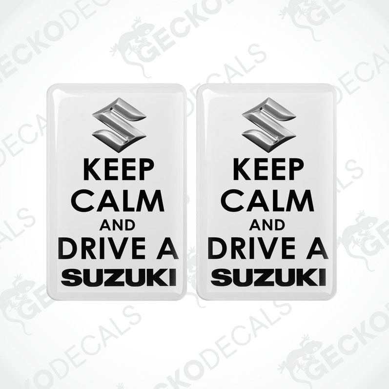 Two withe vinyl stickers with the text 'KEEP CALM AND DRIVE A SUZUKI' and the Suzuki logo.