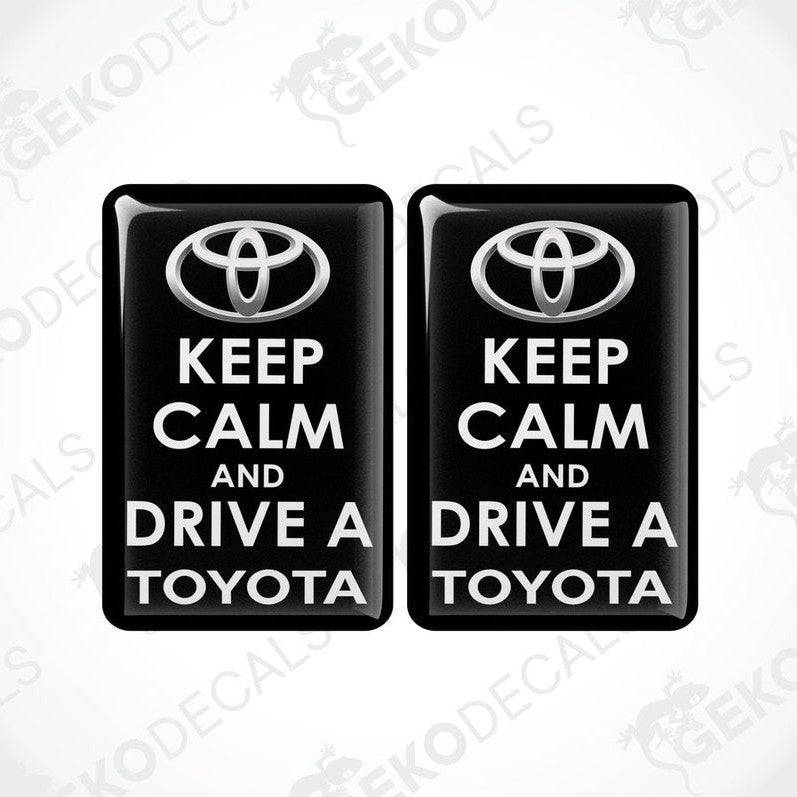 Two rectangular black vehicle decals with white text that read 'KEEP CALM AND DRIVE A TOYOTA', including the Toyota logo.