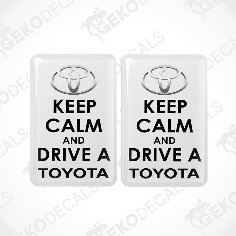 Two rectangular withe vehicle decals with black text that read 'KEEP CALM AND DRIVE A TOYOTA', including the Toyota logo.