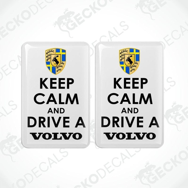 Two rectangular withe vinyl decals with the text 'KEEP CALM AND DRIVE A VOLVO' in white letters, and the Volvo car logo in yellow and blue.